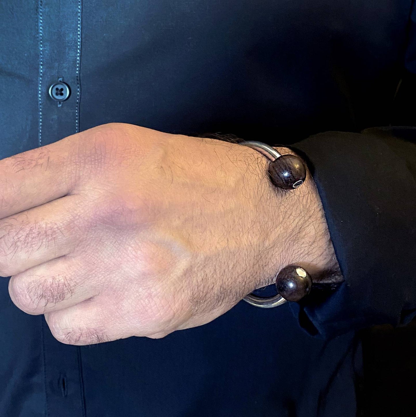 man's hand wearing Silverwood's wood and silver torque bangle black wood