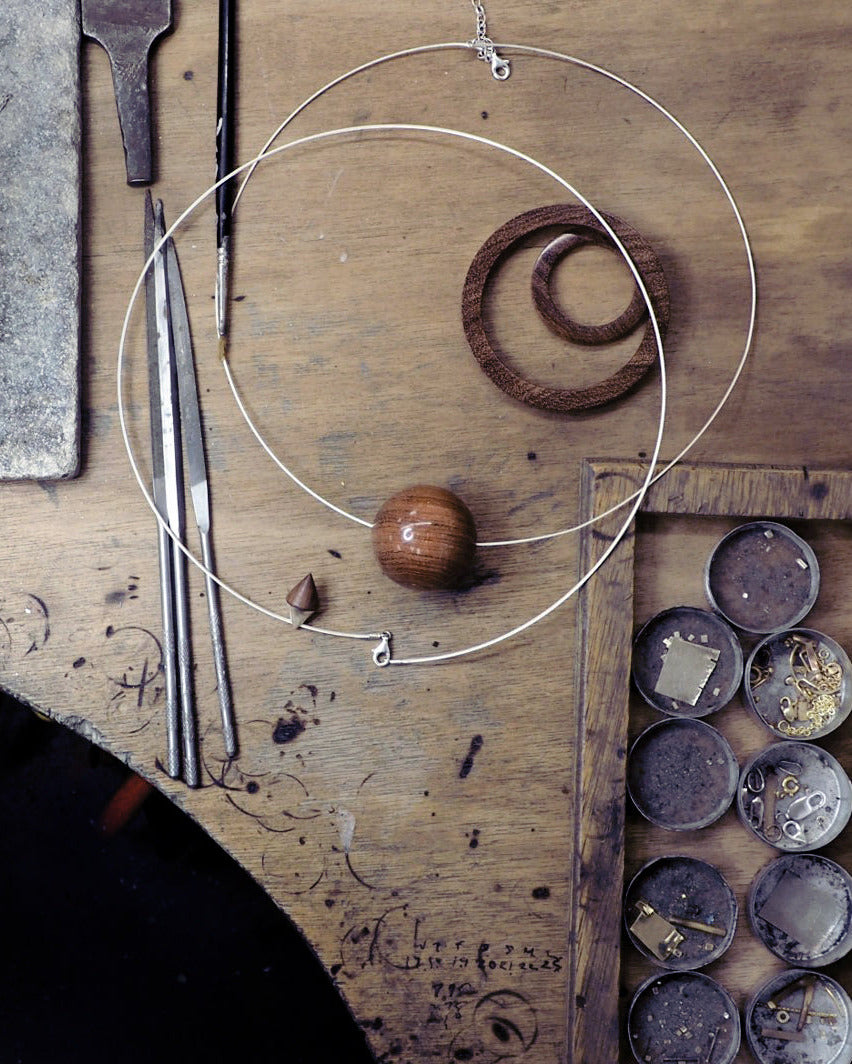 jeweller's bench with large wood bead and silver chain on table