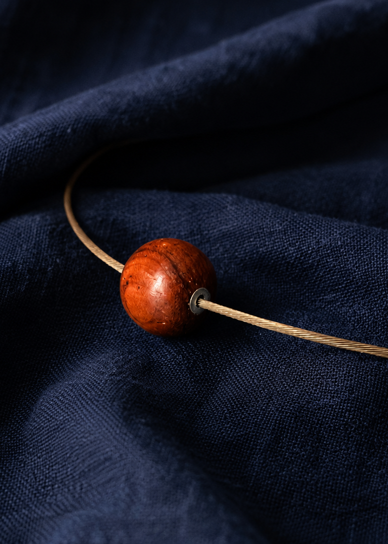 red wood bead on chain with silver detail on dark blue background