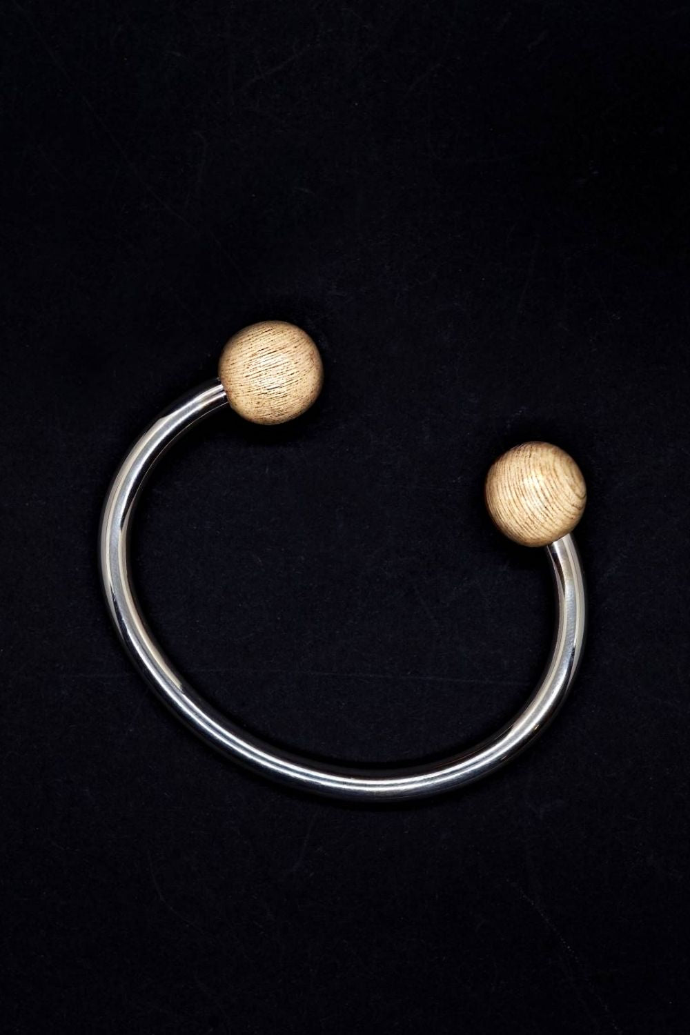Silver bracelet with wood beads on a black background