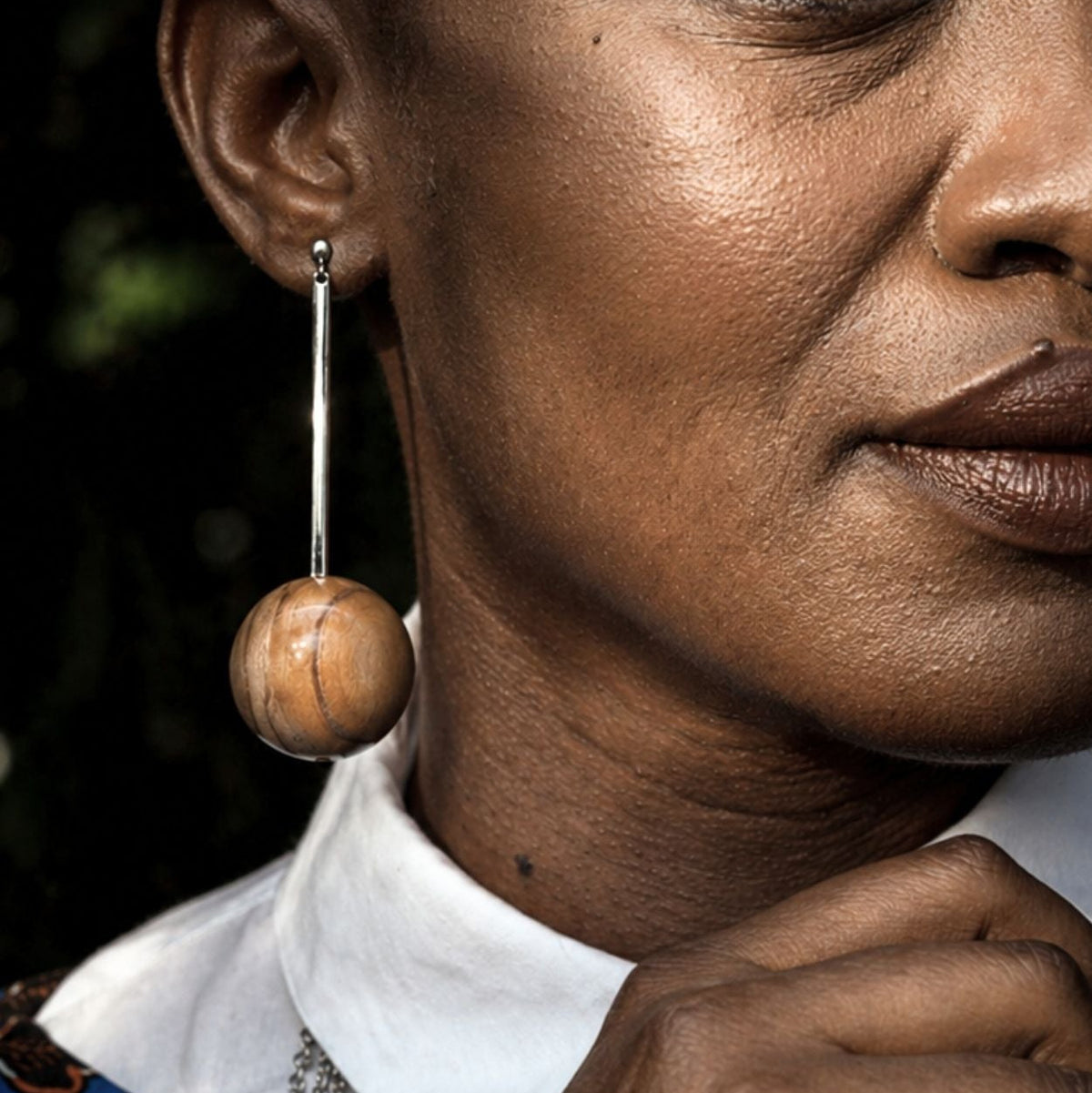 Close-up of a person wearing large wooden earrings with a blurred background