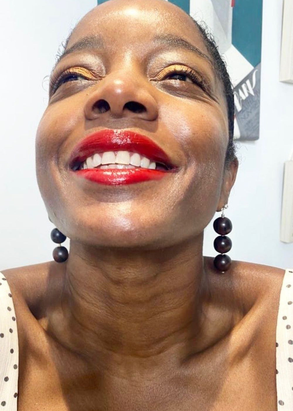 Woman with red lipstick and earrings against a neutral background