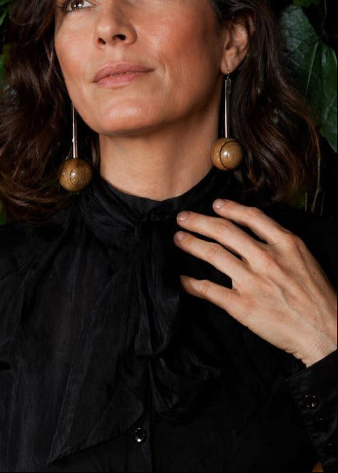 Woman wearing large wooden earrings with a dark background