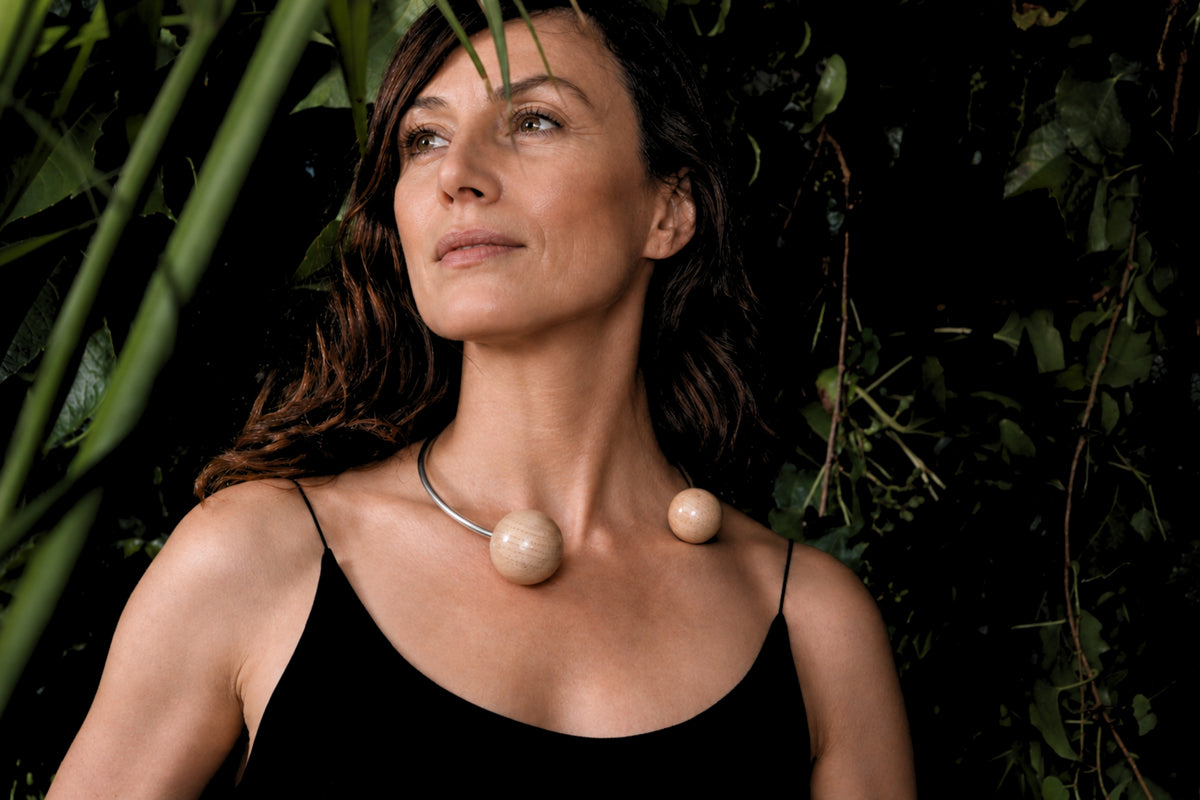 Woman wearing a pearl necklace against a dark green leafy background