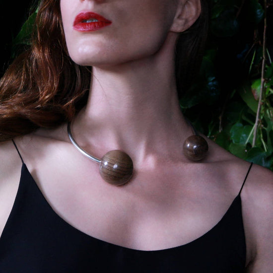 Model wearing the Gaia Double Sphere Torque Necklace by Silverwood Jewellery with large wooden spheres beads in walnut and sterling silver torque necklace